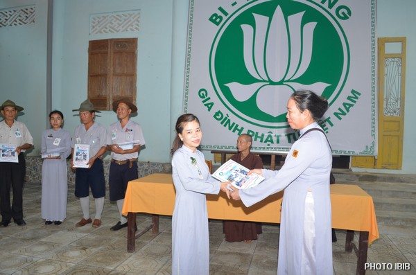 Chị Huynh trưởng Tôn Nữ Thị Hương, Phó Ban Hướng Dẫn, trao Giải thường về thành tích học tập cho các Trại sinh trúng cách, Nữ Htr.Trại sinh này đã ôm con nhỏ đến tham dự Trại Huyền Trang